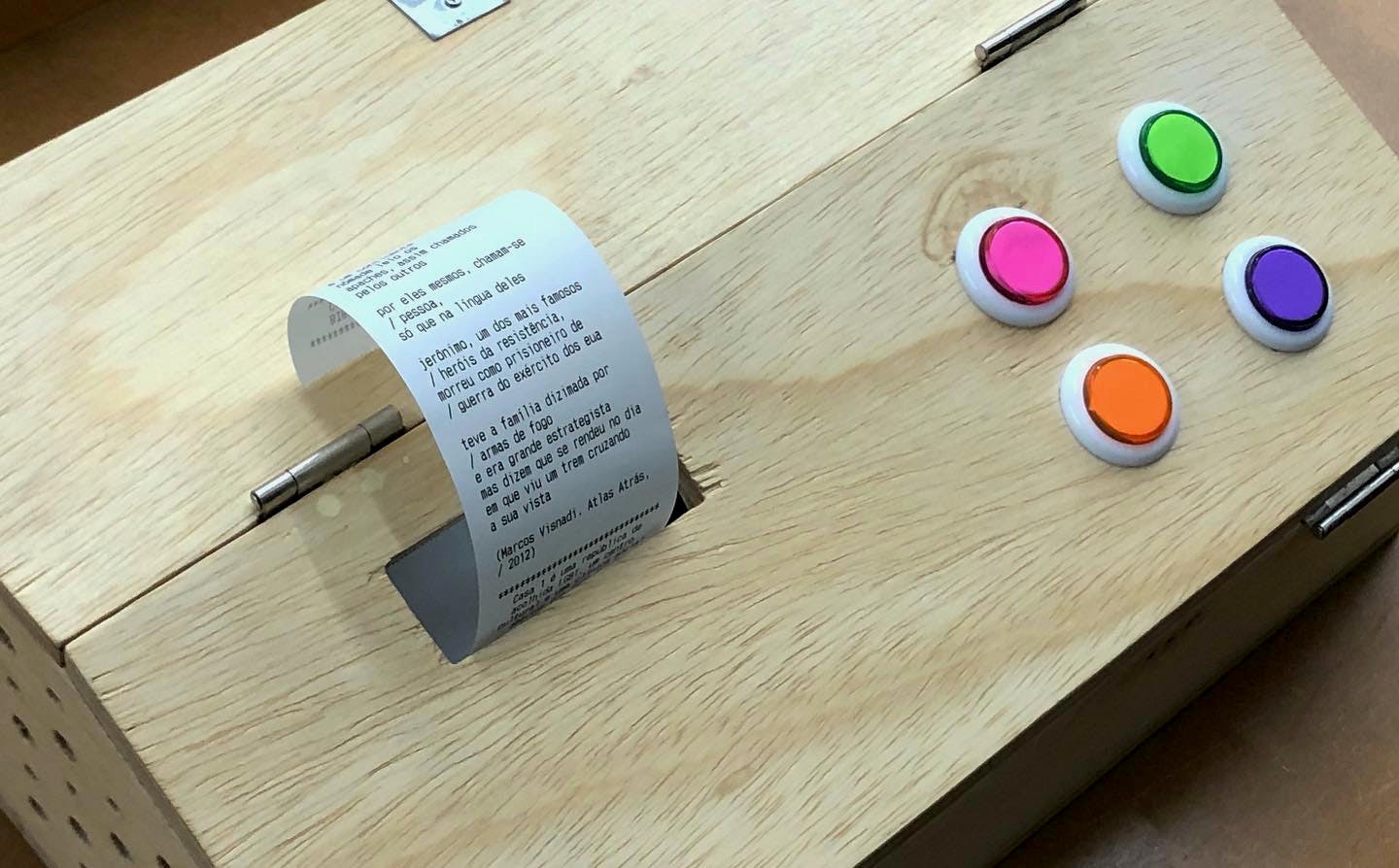 A picture of Recibo box, with four coloured buttons and a poem being printed.