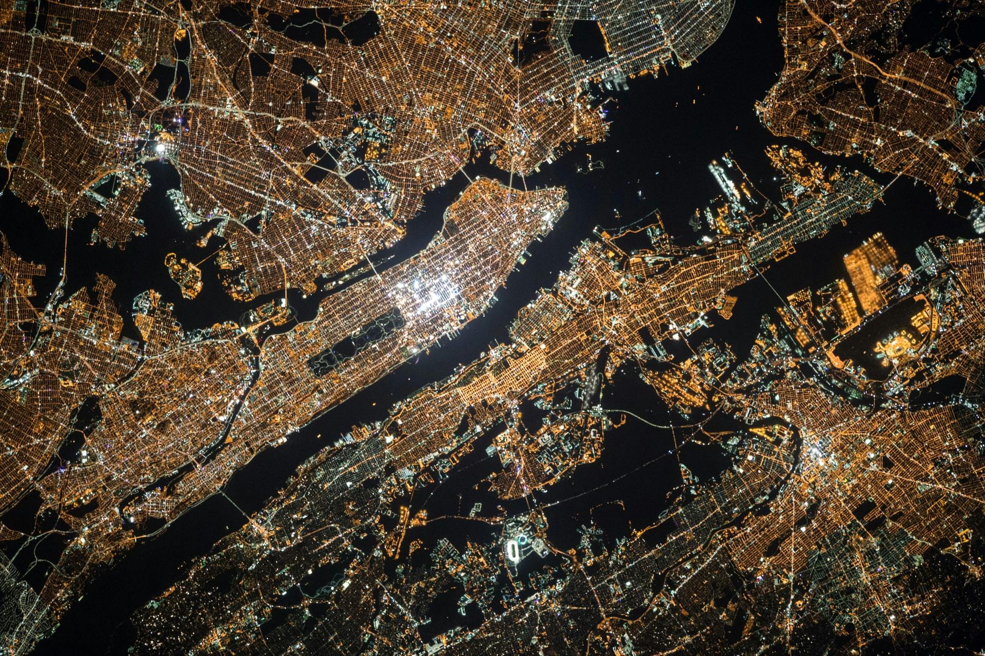 Aerial photo of a city at night. By NASA on Unsplash